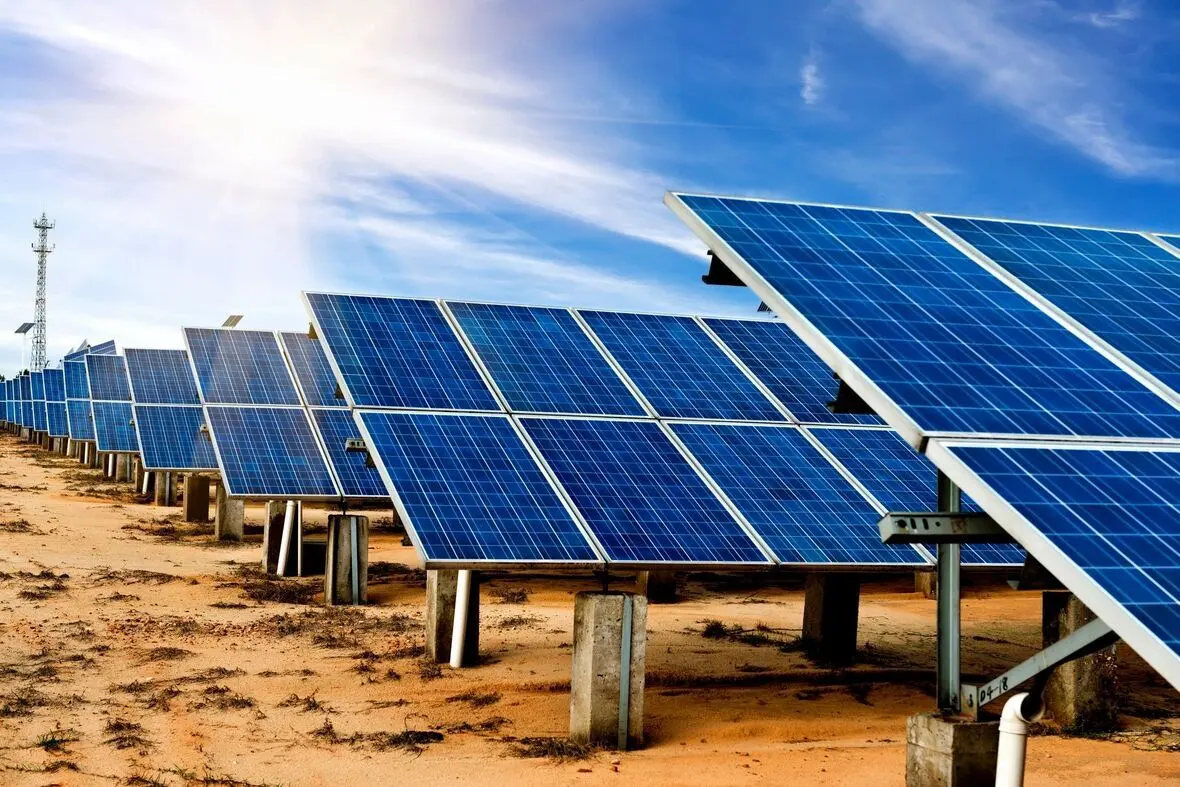Rows of ground-mounted commercial solar panels under a bright sun